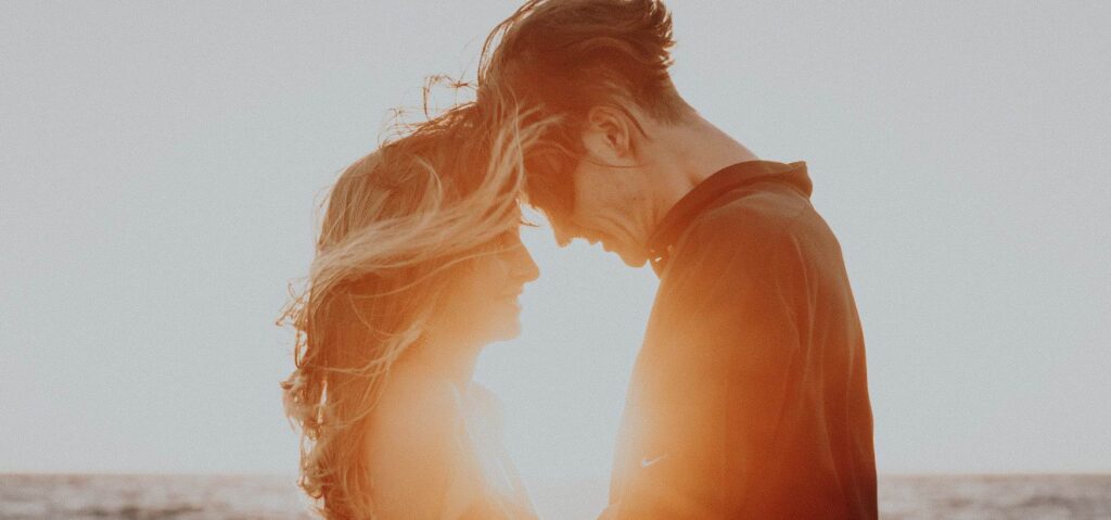 Young couple in love in front of a romantic sunset.