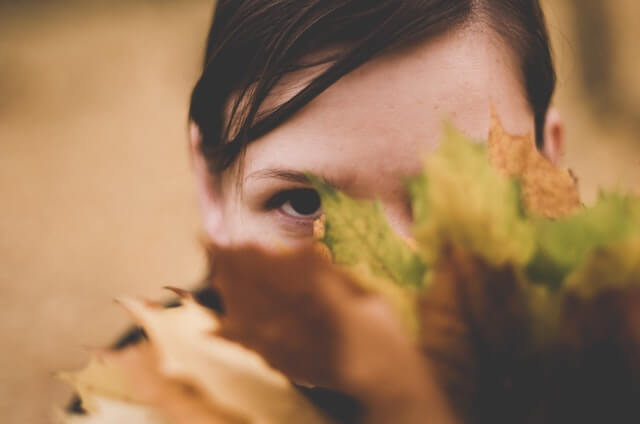 Attractive shy and introverted lady with Asperger hiding behind a bush. 